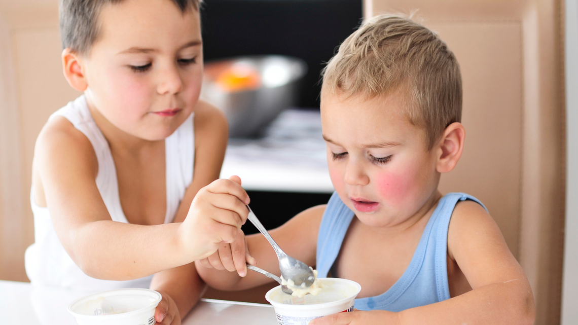 Zwei Jungen essen ein Jogurt mi hohem Zuckergehalt