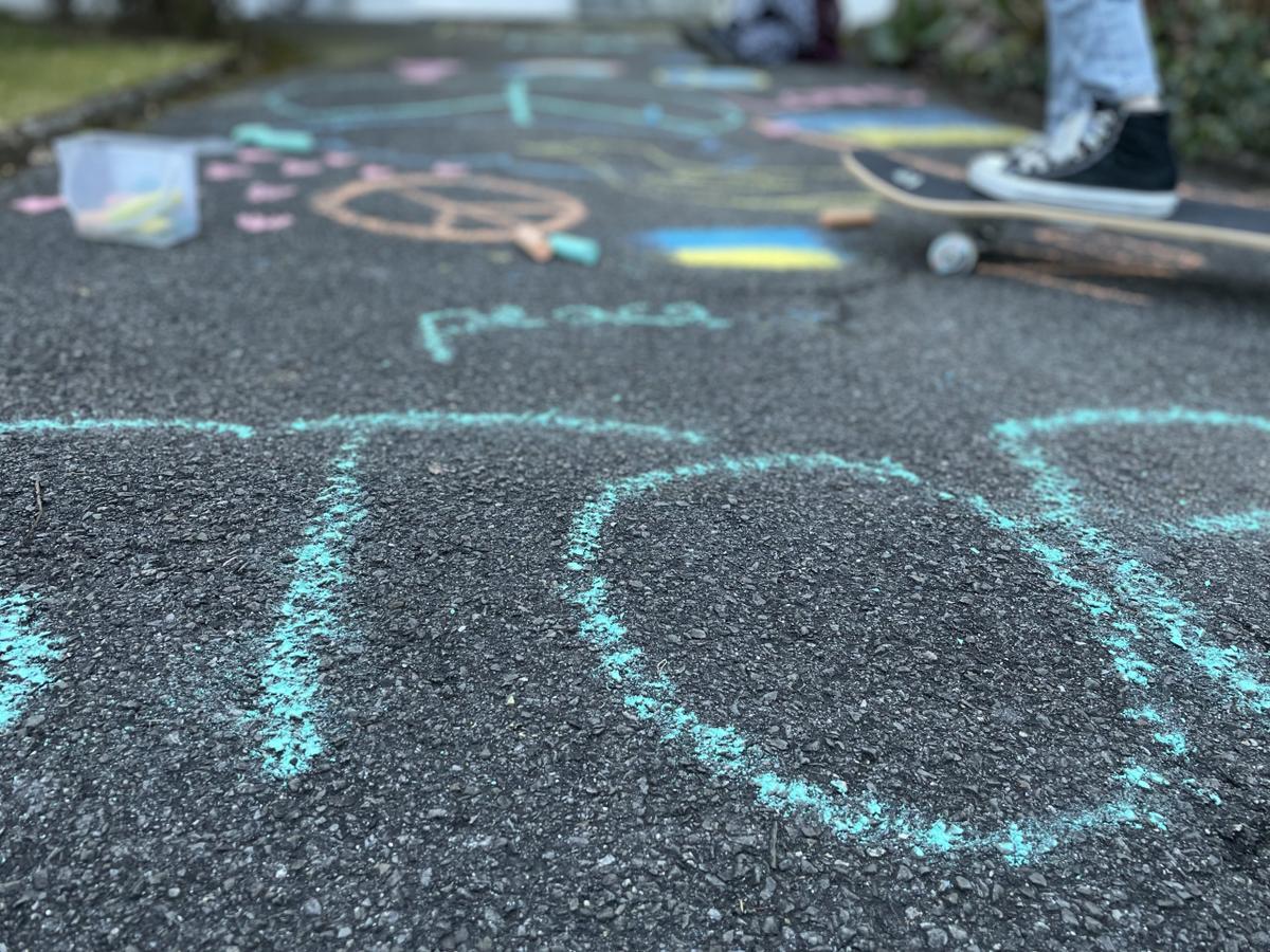 Die Kinder malen Friedenssymbole auf die Strasse.