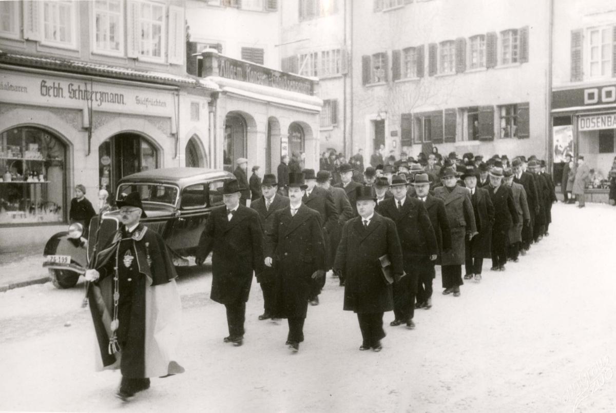 Zu Beginn der neuen Legislatur am 26.12.1938 begeben sich, angeführt vom Standesweibel und dem Kantonsratspräsidenten Augustin Lusser (vorne Mitte), die Kantonsräte nach der Vereidigung in den Kantonsratssaal.