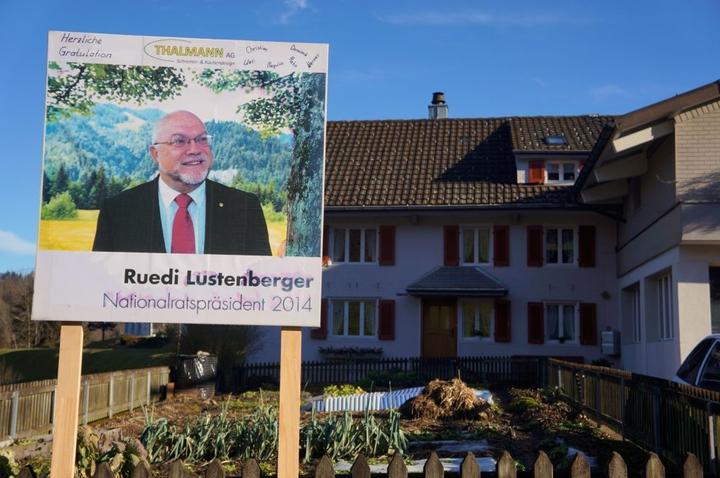 Ein Schild macht darauf aufmerksam, dass hier der höchste Schweizer wohnt. In diesem Haus ist Ruedi Lustenberger geboren und aufgewachsen. Und er wohnt immer noch hier.
