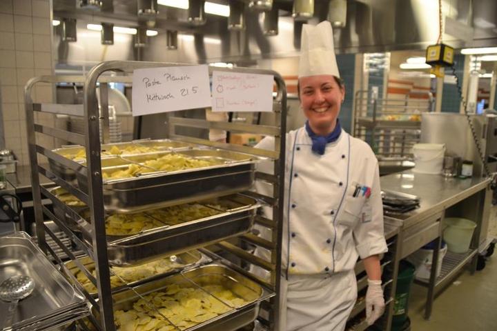 Eine Küchenmitarbeiterin präsentiert frische Pasta.
