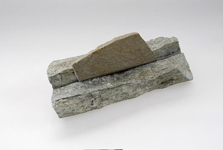 Angesägter Stein und Sägeplättchen aus Sandstein nach Art der Pfahlbauer, moderne Werkstücke.