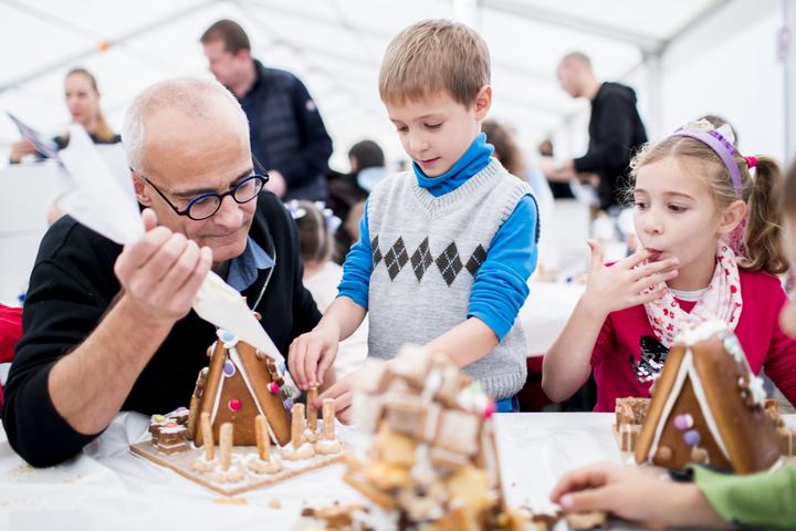 <p>CEO der HUG AG, Andreas Hug (links), verziert zusammen mit einem Kind ein Lebkuchenhaus.</p>