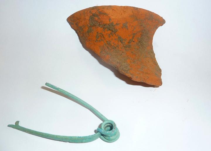 <p>Zwei der Funde aus dem 1. Jahrhundert vor Christus: eine Fibel (Gewandnadel) aus Bronze und ein Keramikstück.</p>