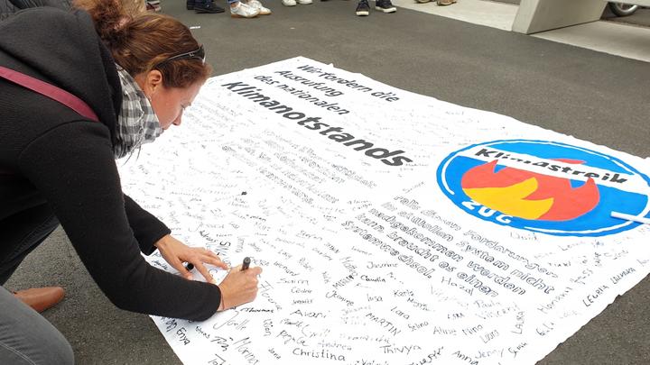 <p>Wer den Klimanotstand im Kanton Zug will, unterschreibt auf dem Transparent.</p>