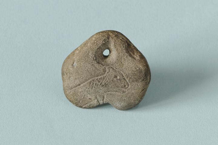 <p>Durchlochter Stein mit eingeritzter Darstellung eines vielleicht katzenartigen Tiers.</p>