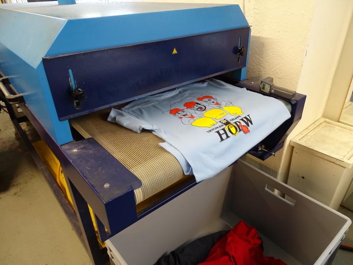 <p>Die fertig bedruckten Shirts kommen auf die Trocknermaschine, wo die Farbe erhitzt und dadurch fixiert wird.</p>